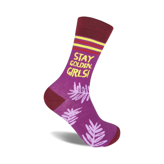 Purple crew socks with maroon cuffs, yellow text reading 'Stay Golden, Girls!', and a light purple leaf pattern.