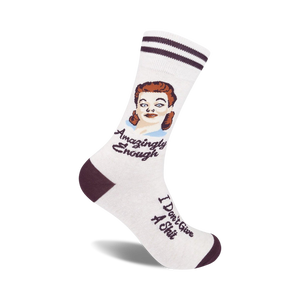 Cream crew socks with maroon stripes and a vintage illustration of a woman. Text reads 'Amazingly Enough' and 'I Don't Give A Shit'.
