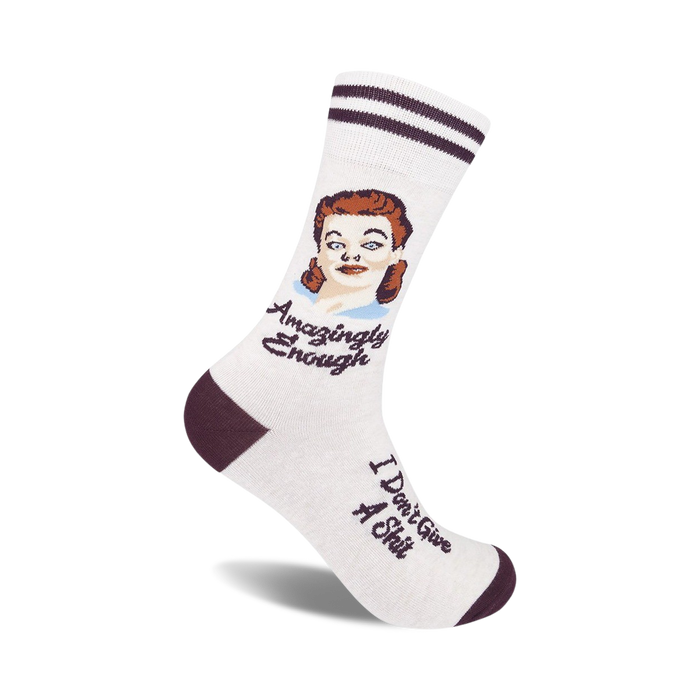 Cream crew socks with maroon stripes and a vintage illustration of a woman. Text reads 'Amazingly Enough' and 'I Don't Give A Shit'.