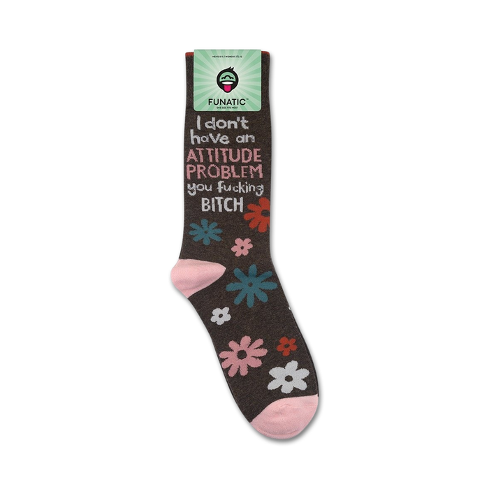 Lifestyle product shot of the 'I Don't Have An Attitude Problem' socks shown on a foot.  The socks are dark brown with pink, teal, and white flowers. The socks also feature a bold sassy message