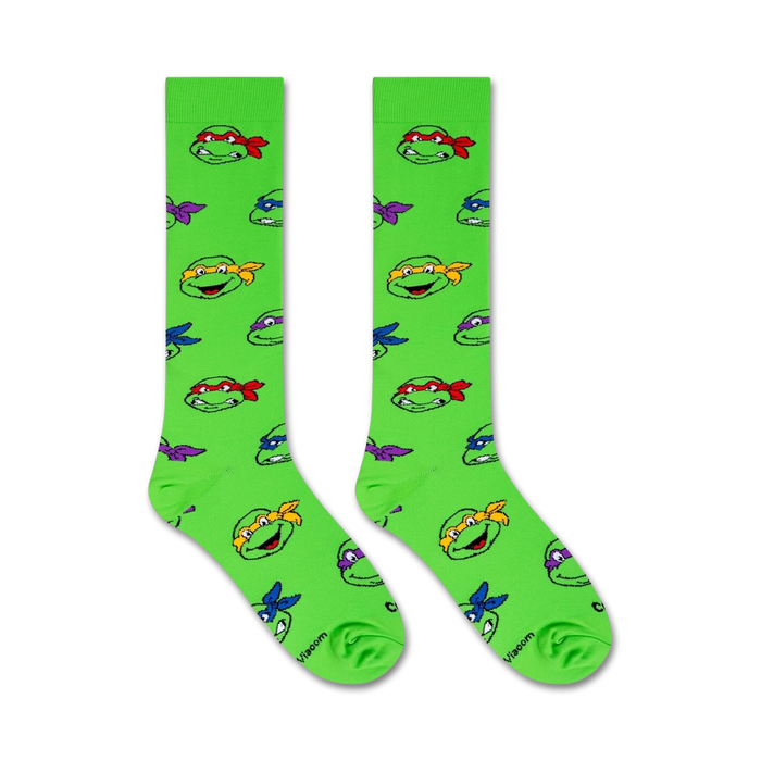 A pair of green socks with a pattern of the Teenage Mutant Ninja Turtles faces.