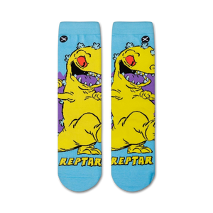 Flat lay showcasing a pair of Rugrats Reptar crew socks. The socks feature a light blue background with a yellow Reptar design.
