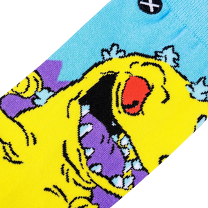 Close-up detail shot of the Rugrats Reptar sock design, highlighting the vibrant yellow, purple, and light blue colors.