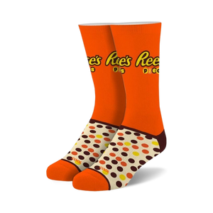 Pair of orange crew socks with Reese's Pieces logo and brown, yellow, and orange polka dots.
