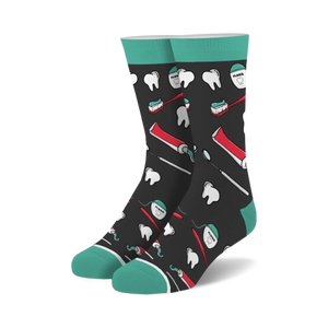 Pair of crew socks with a dark background and teal cuffs.  The design features illustrations of teeth, toothbrushes, toothpaste tubes, and dental floss.
