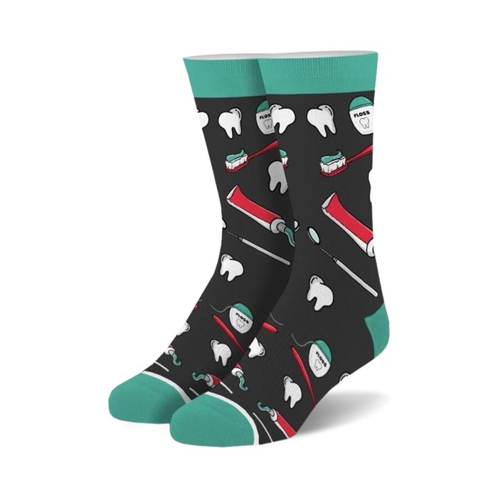 Pair of crew socks with a dark background and teal cuffs.  The design features illustrations of teeth, toothbrushes, toothpaste tubes, and dental floss.