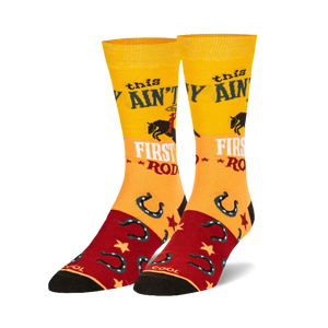 Pair of crew socks in yellow, red, and black.  Features a cowgirl riding a horse, horseshoes, and the text 'This ain't my first rodeo'.