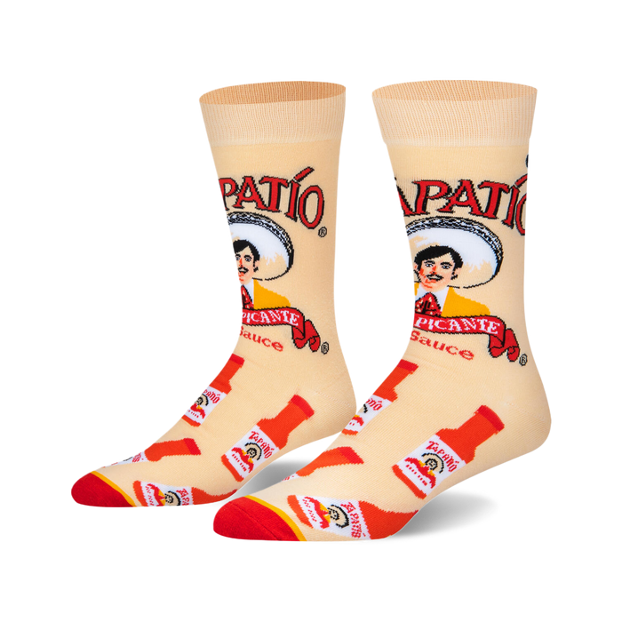 Pair of crew socks, beige background with red and white Tapatio hot sauce bottles and logo, featuring the Tapatio man.