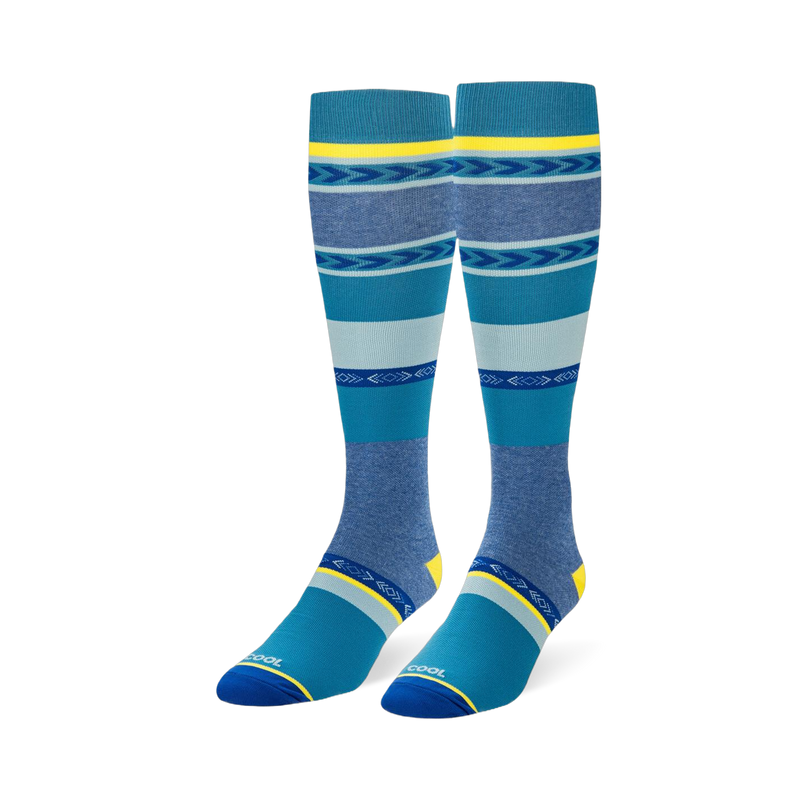 Knee-high socks featuring wide teal, navy, and heather blue stripes mixed with geometric arrow patterns and yellow accents.