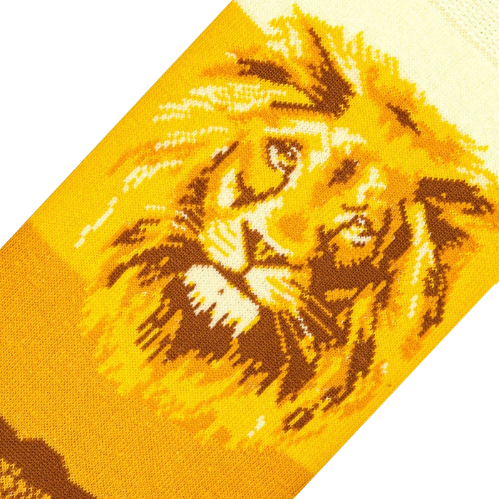 A close up of a knitted image of a lion's face in brown and yellow on a black background.