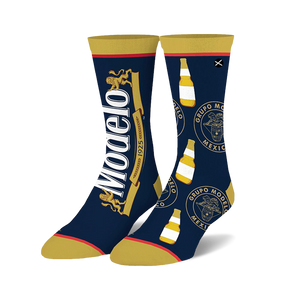 Pair of Modelo Split crew socks in navy blue and gold. Features Modelo logo and bottle graphic repeats.