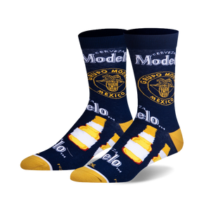 Pair of crew socks in navy blue, featuring Modelo beer bottle and logo graphics in yellow and white.
