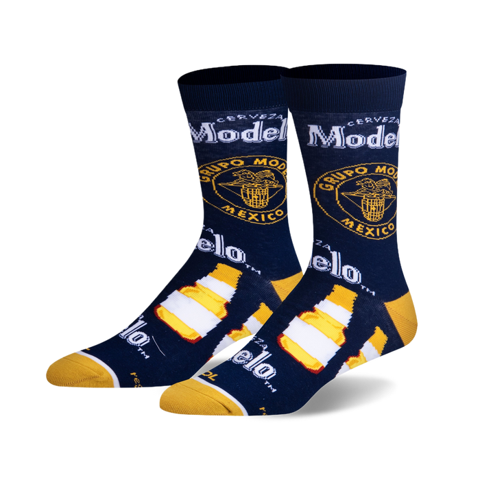 Pair of crew socks in navy blue, featuring Modelo beer bottle and logo graphics in yellow and white.