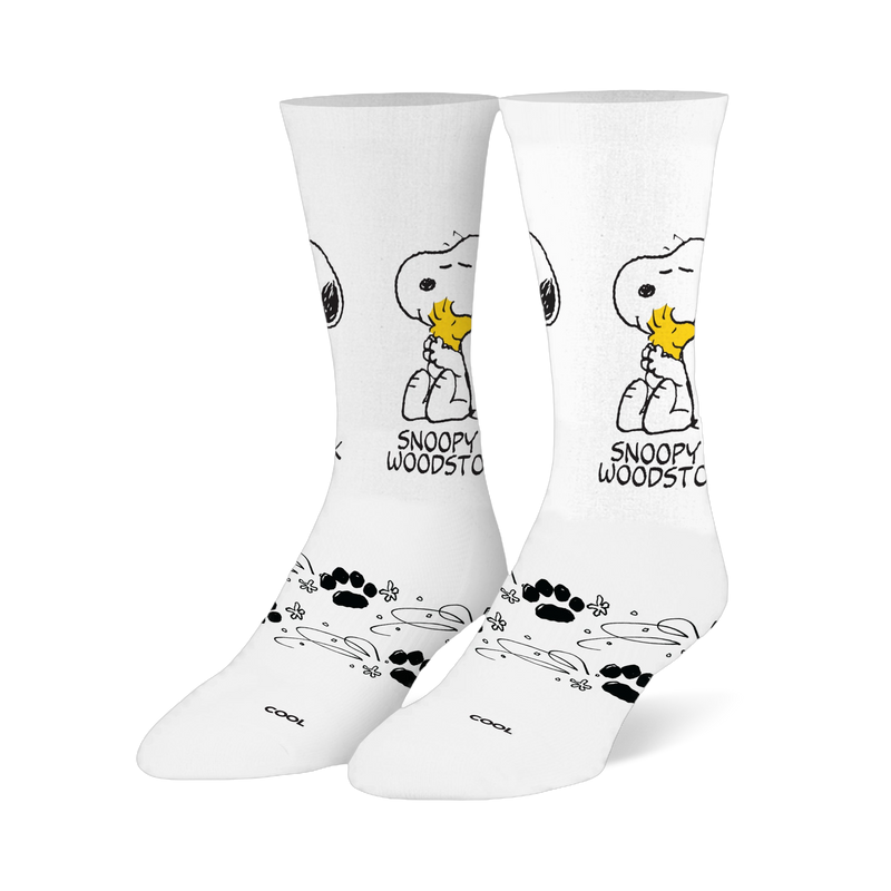 White crew socks showing Snoopy hugging a yellow Woodstock, with black paw prints and swirling line patterns on the foot.