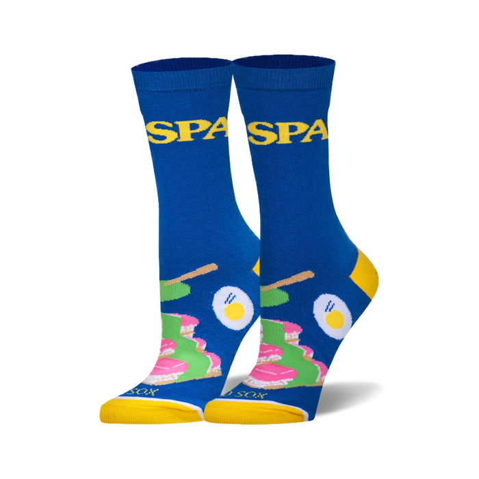 Pair of blue crew socks with yellow cuffs. Features a fun spa-themed design with images of cakes, eggs, and chopsticks, and the word 'Spa' repeated. }}