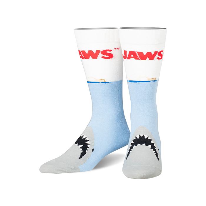 A pair of crew socks, predominantly light blue and white, feature the 'JAWS' title and a shark's mouth emerging from the water. }}
