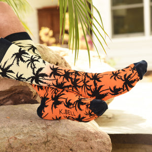 A person is modeling a pair of orange and black palm tree socks. The socks are folded over showing the 