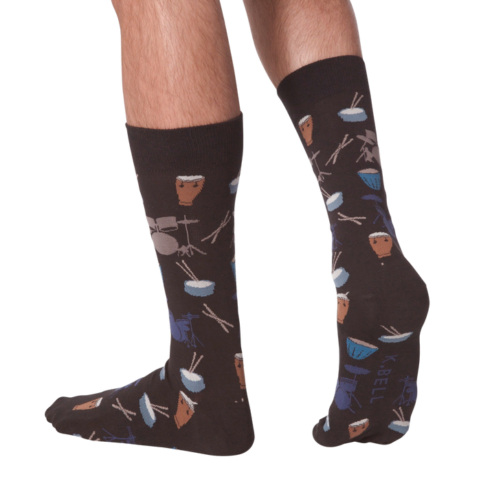 Lifestyle shot showing the 'Drums' socks on a person's legs from the back. The socks are dark brown with a drum set pattern.