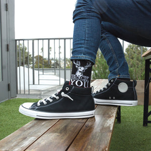 Lifestyle shot: A person wearing 'Buck You' socks and black high-top sneakers.