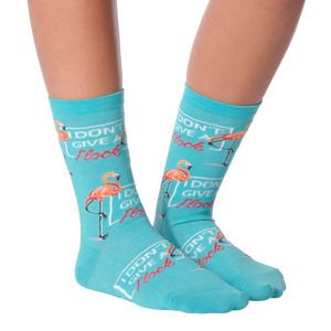 A pair of teal socks with a flamingo design. The flamingo is standing on one leg and has the words 