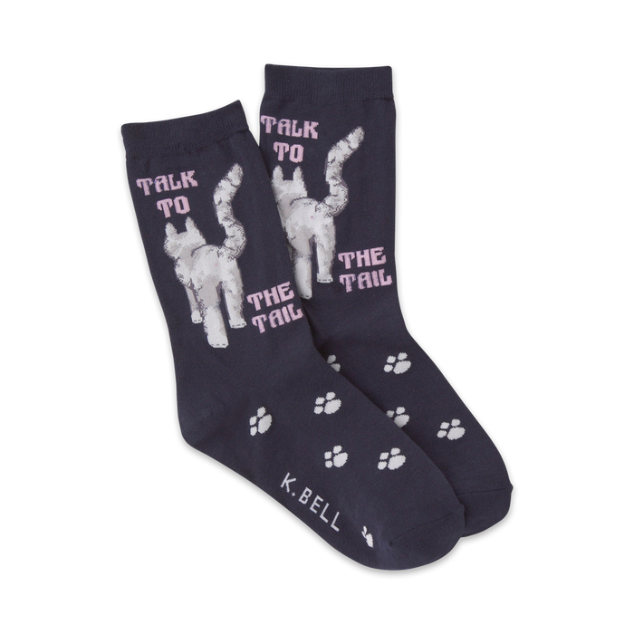 Pair of navy blue crew socks with a whimsical design. Features a white cat's rear and the text 'Talk to the tail' in pink, plus small paw prints. }}