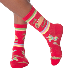 Lifestyle shot: Woman's legs wearing the 'Let's Taco Bout It' socks while casually holding a taco.