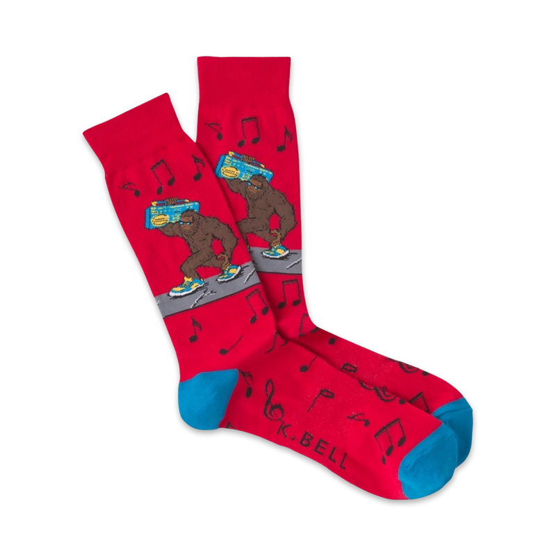 Pair of red crew socks with a cartoon Bigfoot carrying a boombox. Musical notes and teal cuffs add to the fun, 80s-inspired design.