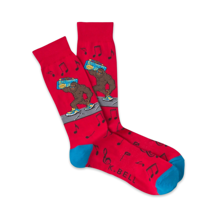 Pair of red crew socks with a cartoon Bigfoot carrying a boombox.  Musical notes and teal cuffs add to the fun, 80s-inspired design.