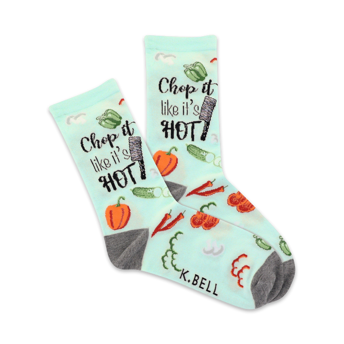 A pair of crew socks on a white background. Light teal socks with a pattern of vegetables and the phrase 'Chop it like it's hot'. Gray heels and toes. }}
