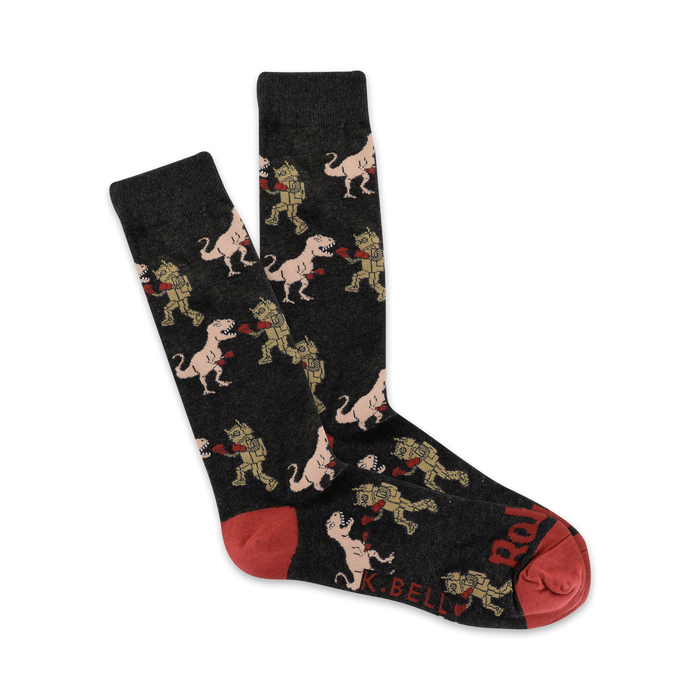 Pair of dark grey crew socks with a repeating pattern of cartoon T-Rexes boxing robots. Red accents on the heel and toe. }}