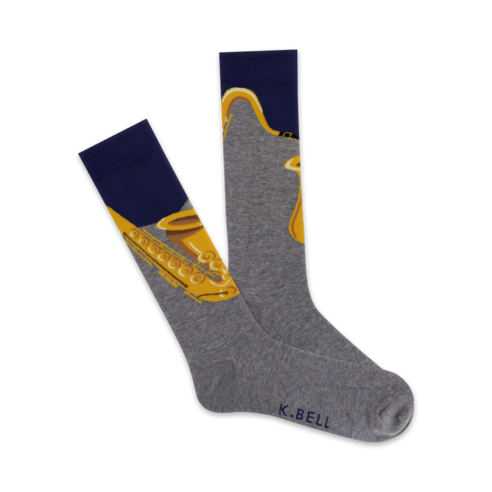 Pair of grey crew socks with a gold saxophone design. The socks have a navy blue cuff. }}