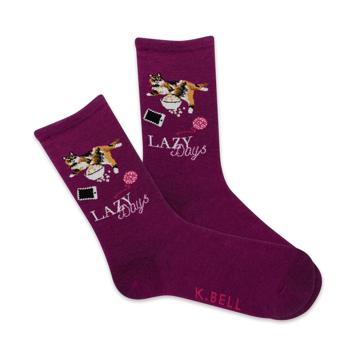 Pair of purple crew socks featuring a calico cat sprawled amidst yarn, a phone, and a bowl. Text reads,