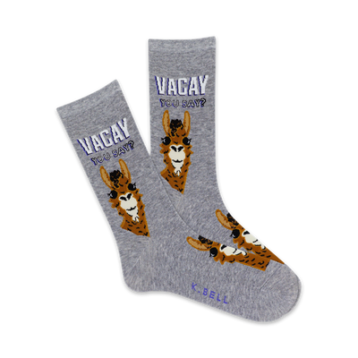 Pair of grey crew socks with brown llama illustrations and the text 'Vacay You Say?' in purple. Fun and quirky design.