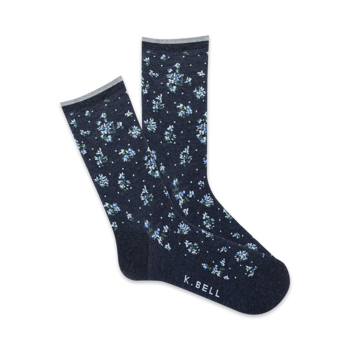 Close-up view of navy blue crew socks with a tiny white floral pattern. Pink trim at the top and 'K.BELL' logo.