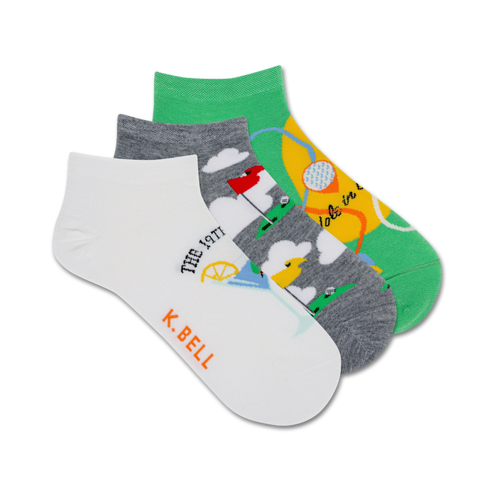 Three ankle socks; one white with golf-themed illustration, one gray with golf course, one green with golf ball. K. Bell logo. }}