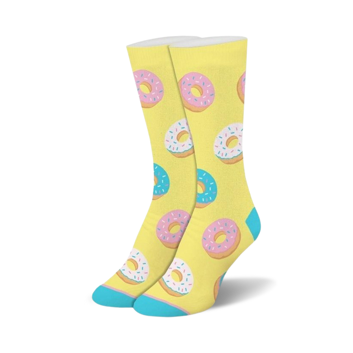A pair of crew socks with a pastel yellow background and a repeating pattern of pink and blue donuts with sprinkles. }}