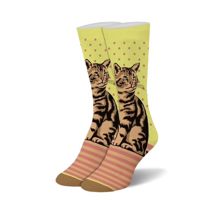 A pair of crew socks showcasing a brown tabby cat design on a lime green background with pink polka dots and stripes. The socks have brown heels and toes. }}