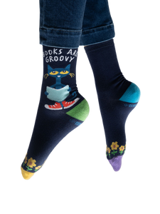 Lifestyle shot of model wearing Pete the Cat socks, showing how they look on feet with jeans.