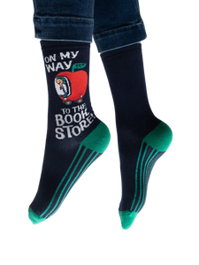 Lifestyle shot: Person wearing navy blue socks with teal stripes and a Richard Scarry apple car design.