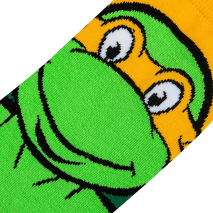 Close-up detail shot of Michelangelo's face on the TMNT crew socks, showing the texture and quality of the print.