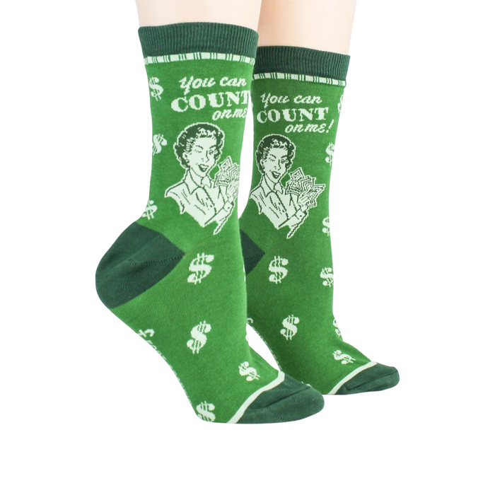 A pair of green crew socks with a pattern of white dollar signs and white text that reads, 
