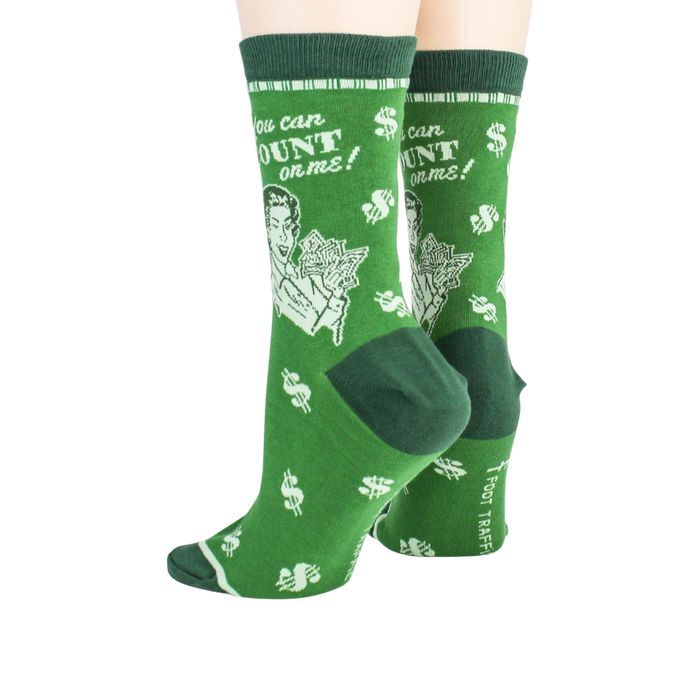 A pair of green crew socks with a pattern of white dollar signs and white text that reads, 