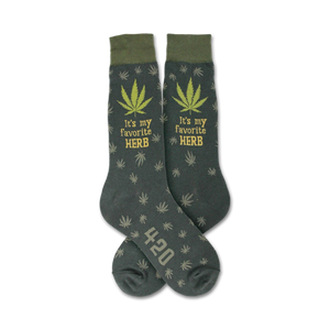 Pair of dark-green crew socks with a repeating cannabis leaf pattern, 'It's my favorite HERB' text, and '420' detail.