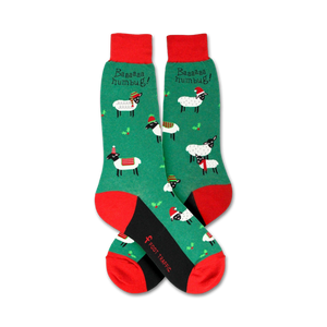 A pair of green and red socks with a pattern of cartoon sheep wearing Santa hats. The socks have a red toe and heel, and a black cuff.