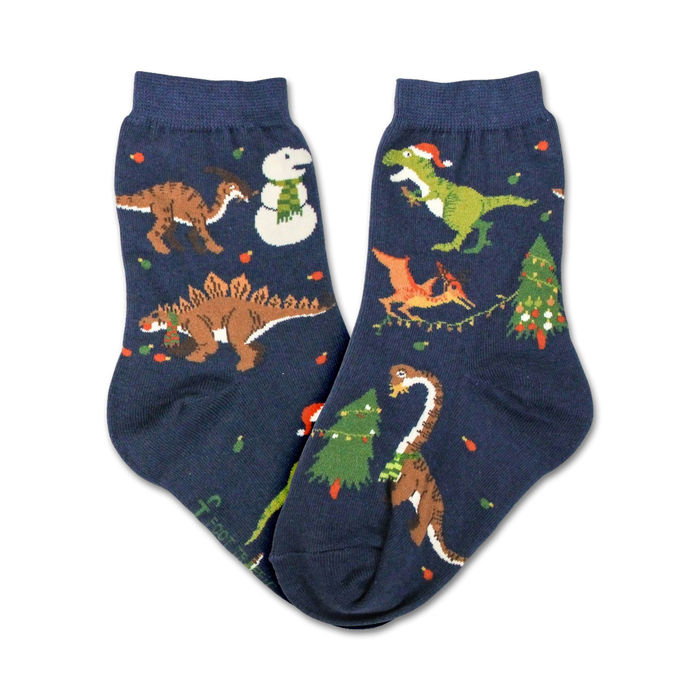 kids christmas tree rex crew socks in dark blue feature holiday dinosaurs in santa hats and christmas lights surrounded by trees and snowflakes.    }}