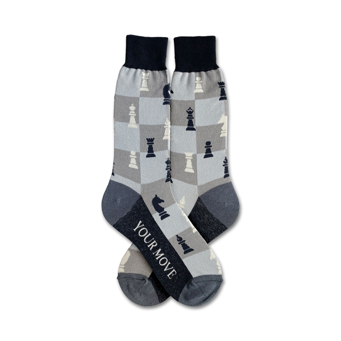 Pair of crew socks in grey and navy blue.  Chessboard pattern features black and white chess pieces.  Text on the socks reads 'Your Move'. }}