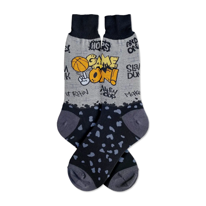 Pair of grey and black crew socks. The socks feature a basketball graphic, graffiti-style text, and black spots on the lower portion. }}