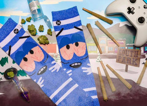 Lifestyle flat lay photo showing Towelie socks, marijuana paraphernalia, an Xbox controller and South Park themed background.