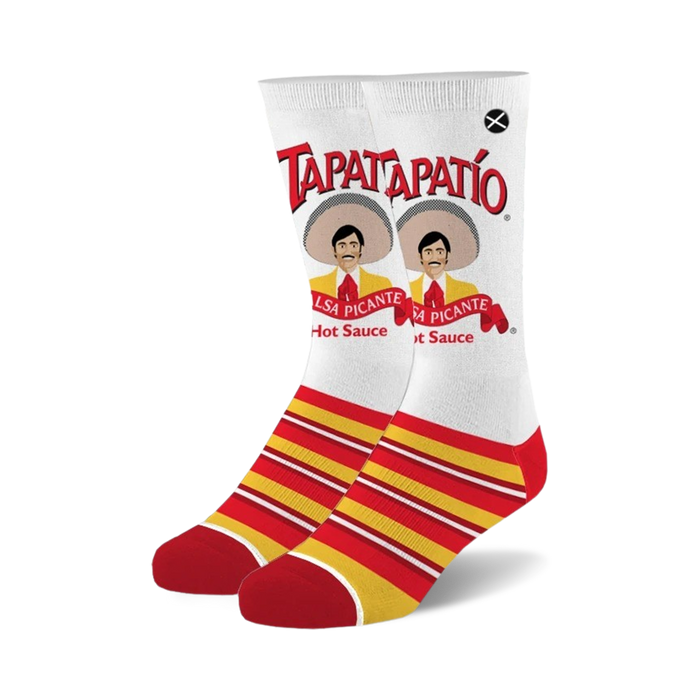 Pair of crew socks with a white background featuring the Tapatio hot sauce logo, a man in a sombrero, and red and yellow stripes at the bottom. }}