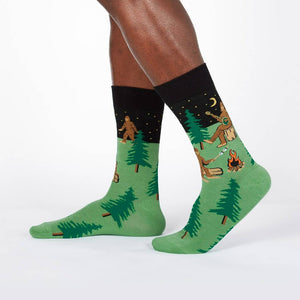 Lifestyle shot showing Sasquatch Camp Out socks on a person's legs, showcasing the design from a slightly different angle.